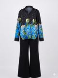 Black shirt with blue and green abstract design and black pants on a white background